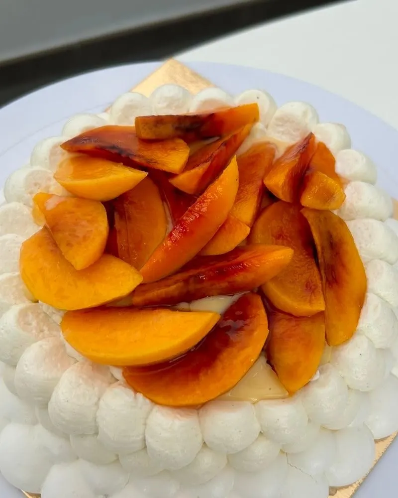 Detalle de los gajos de melocotón asado brillantes sobre los picos de merengue.